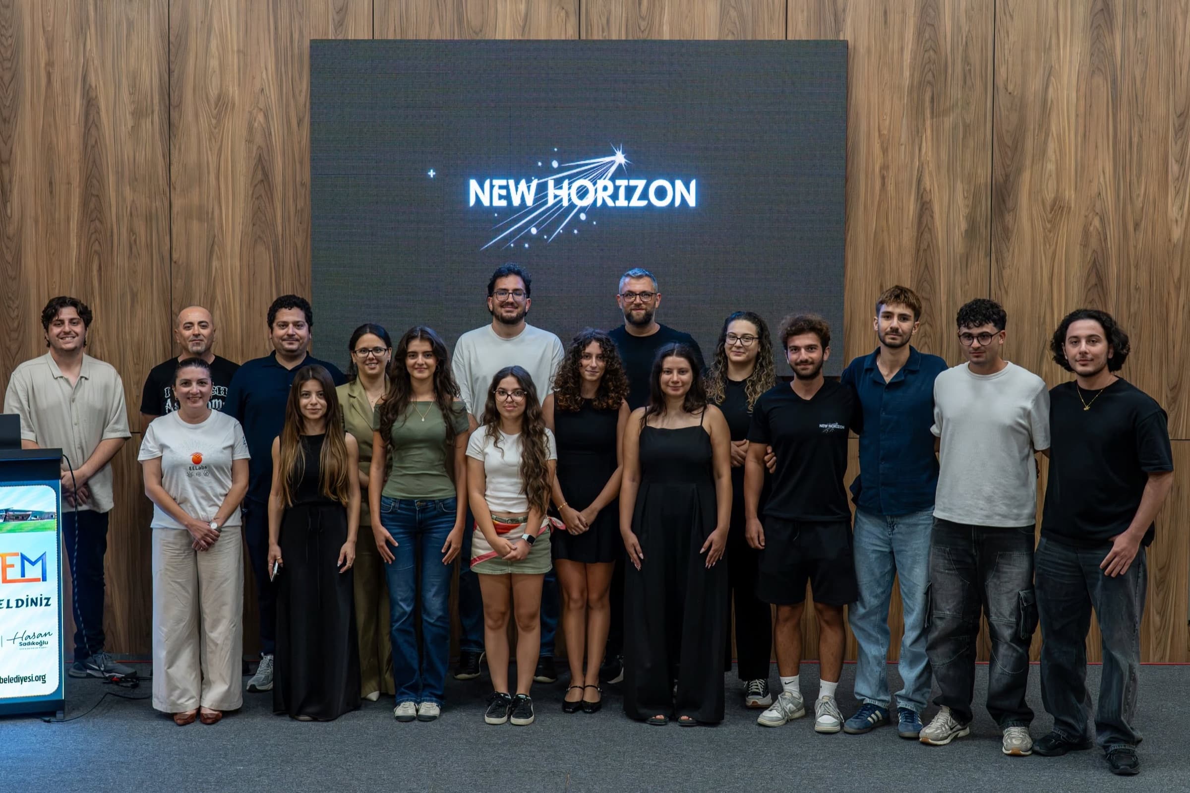 The New Horizon team and participants in a group photo in front of the logo